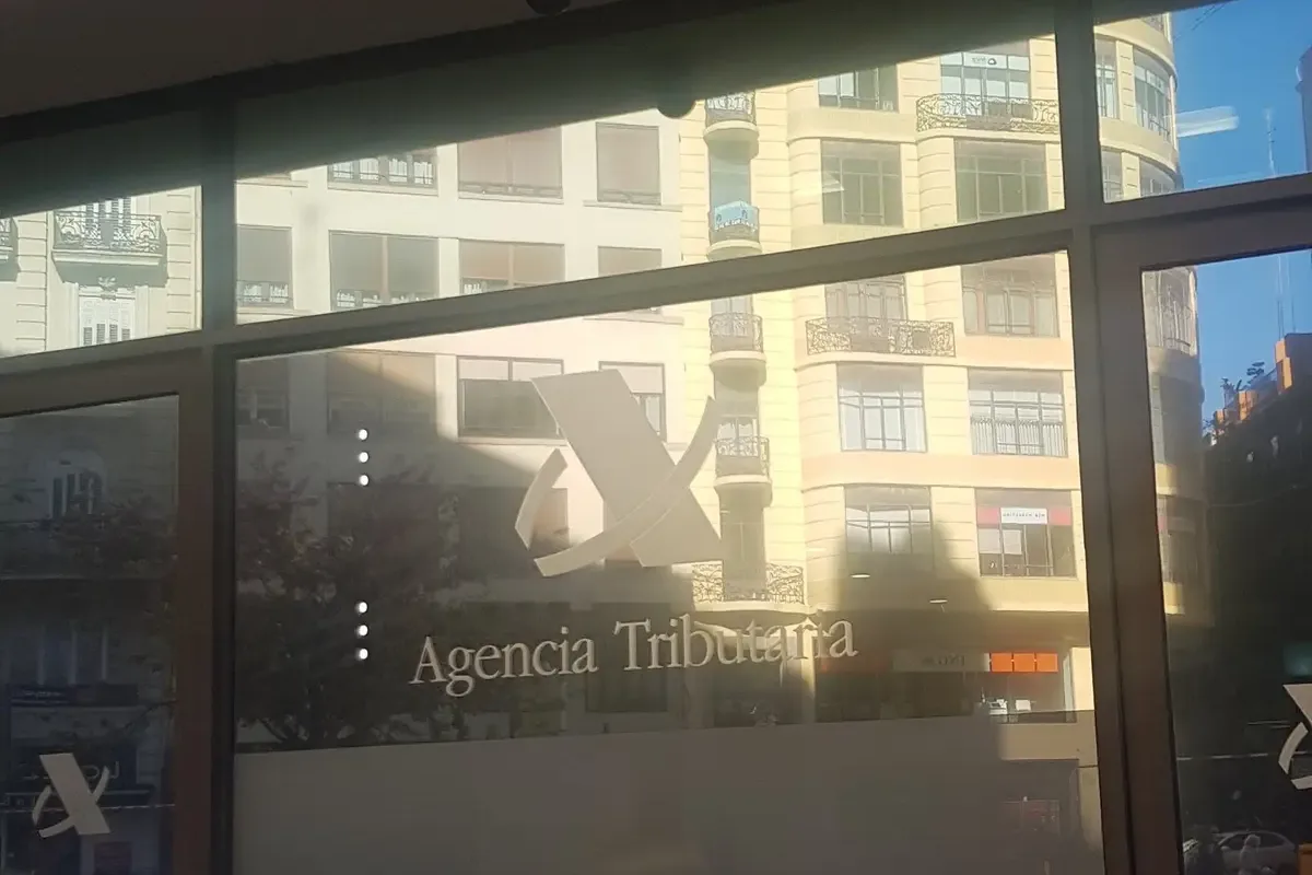 Glass entrance door of a tax office with the Agencia Tributaria logo and the words entrada and salida.