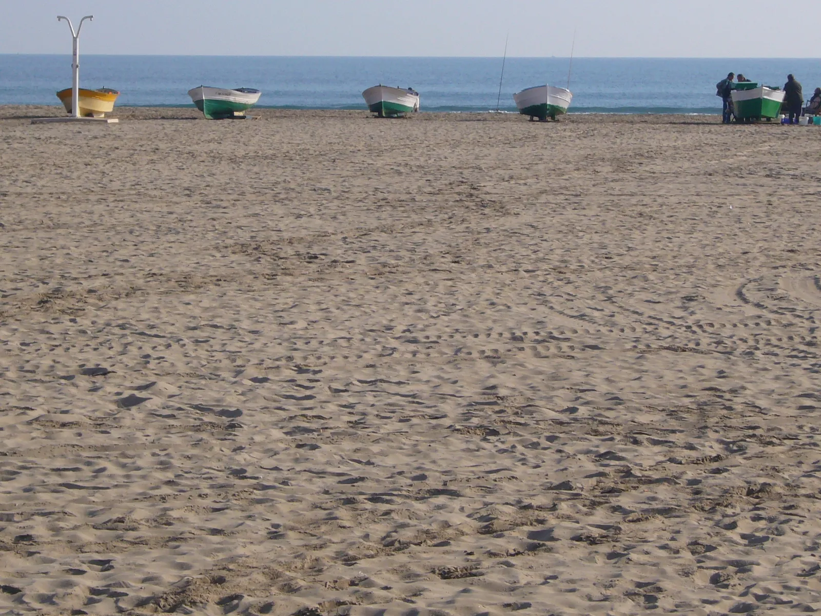 Sand of Platja de la Malva-rosa with small fishing boats pulled up on the beach.