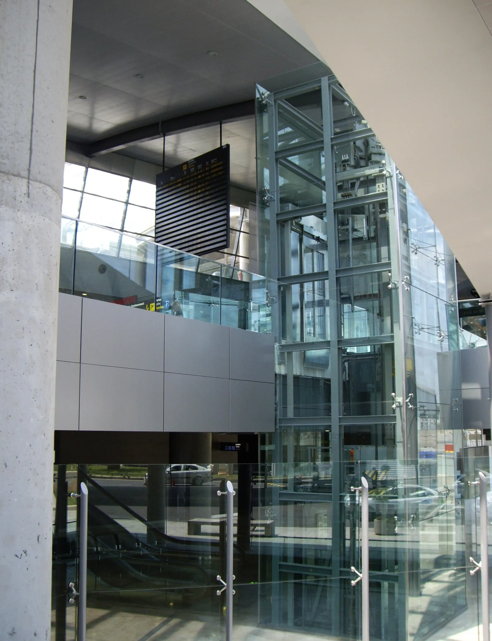 Glass-walled lift and escalators inside an airport terminal building
