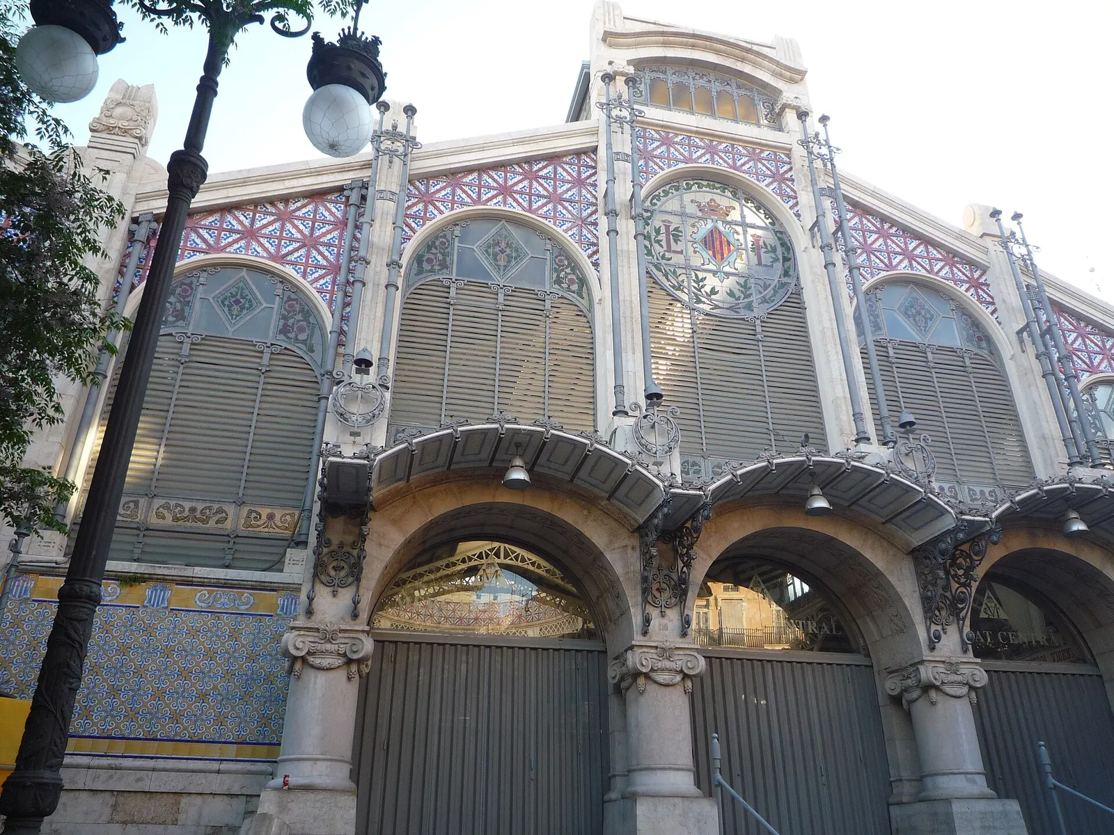Decorated tiled and glass facade of a covered market hall with arched entrances