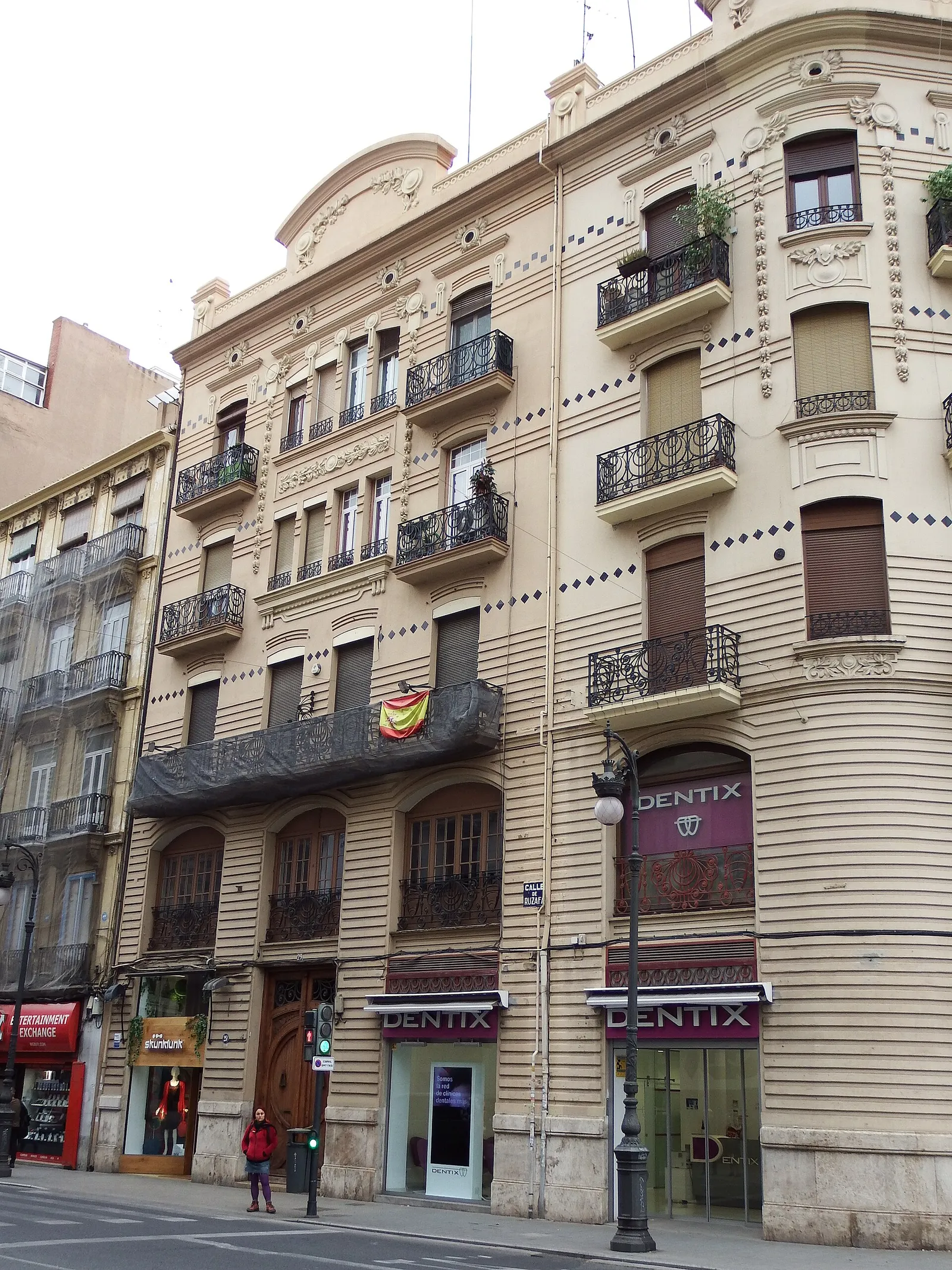 Tall residential building with balconies and shops on the ground floor on a Valencia street
