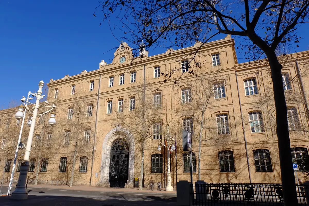 Long brick facade of the former Tabacalera building with a lamp post in front