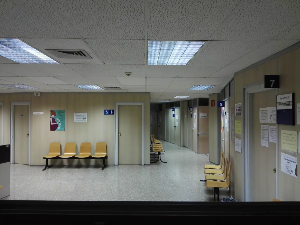 Empty waiting area with yellow chairs along a corridor in a health centre