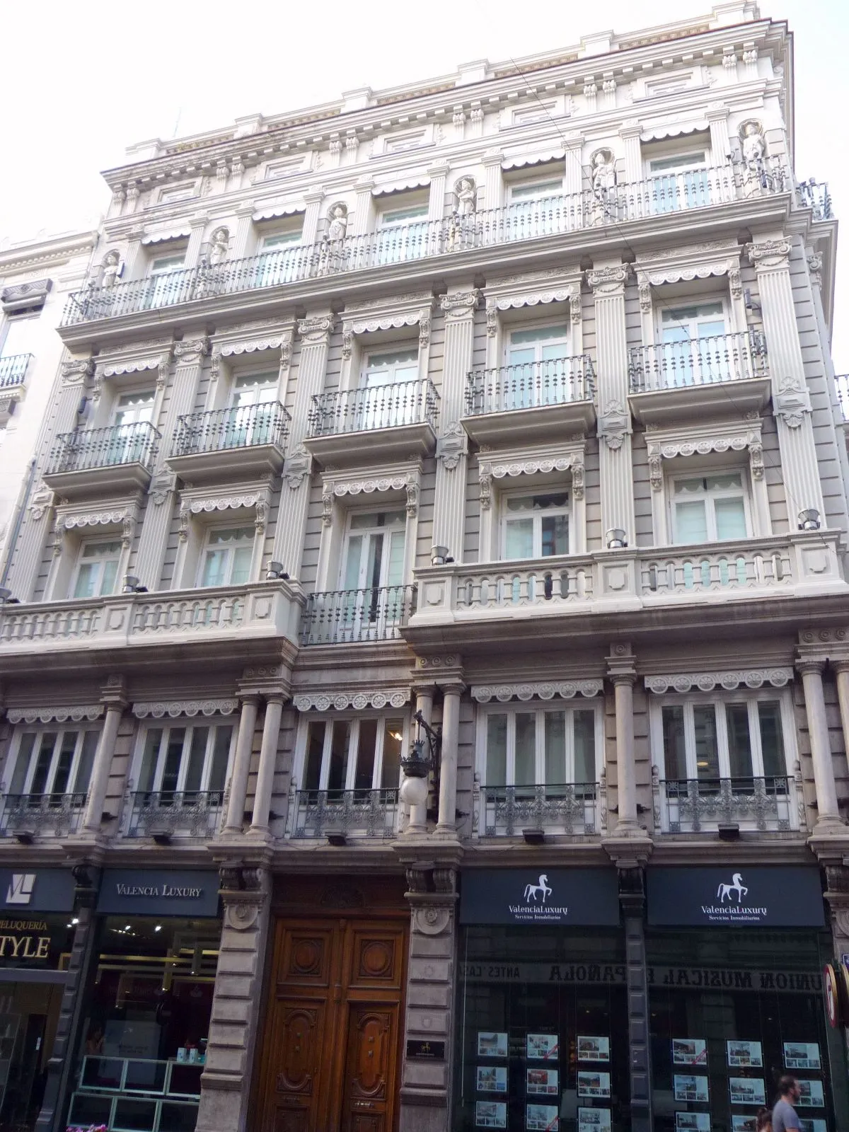 Narrow central street in Valencia lined with apartment buildings and shopfronts.