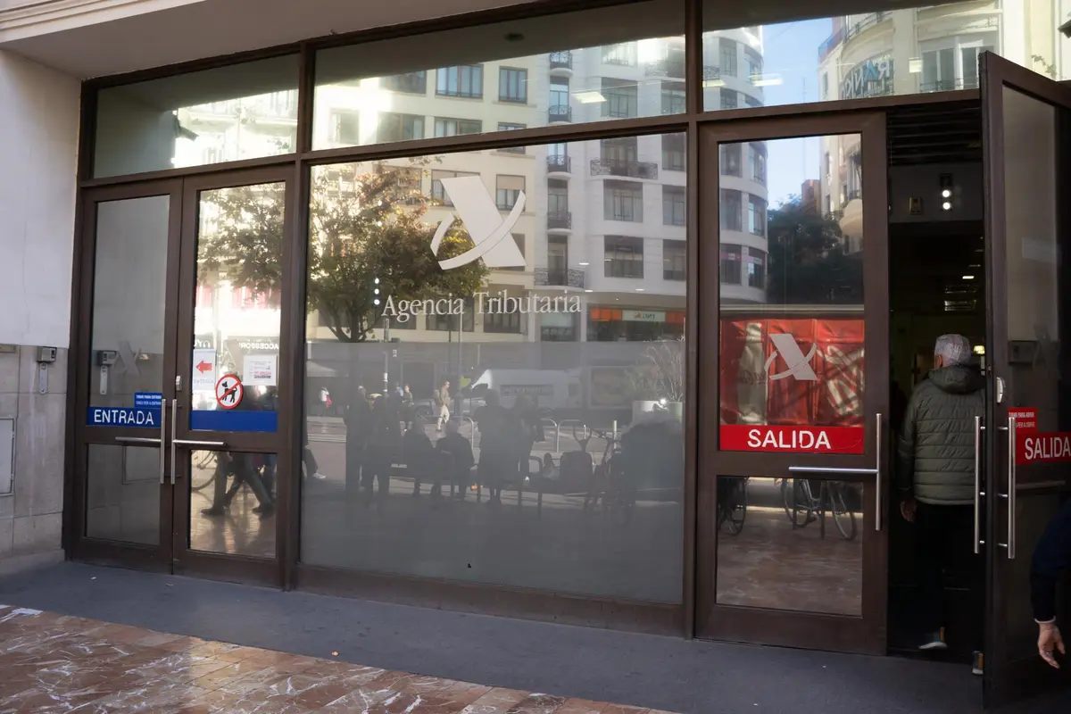 Glass entrance doors of a tax office with the Agencia Tributaria logo and a sign for entry and exit.