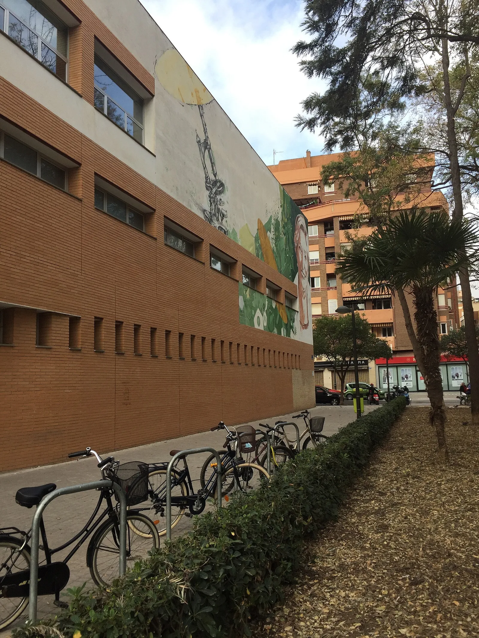 Brick health centre building with a bicycle rack and trees along the pavement