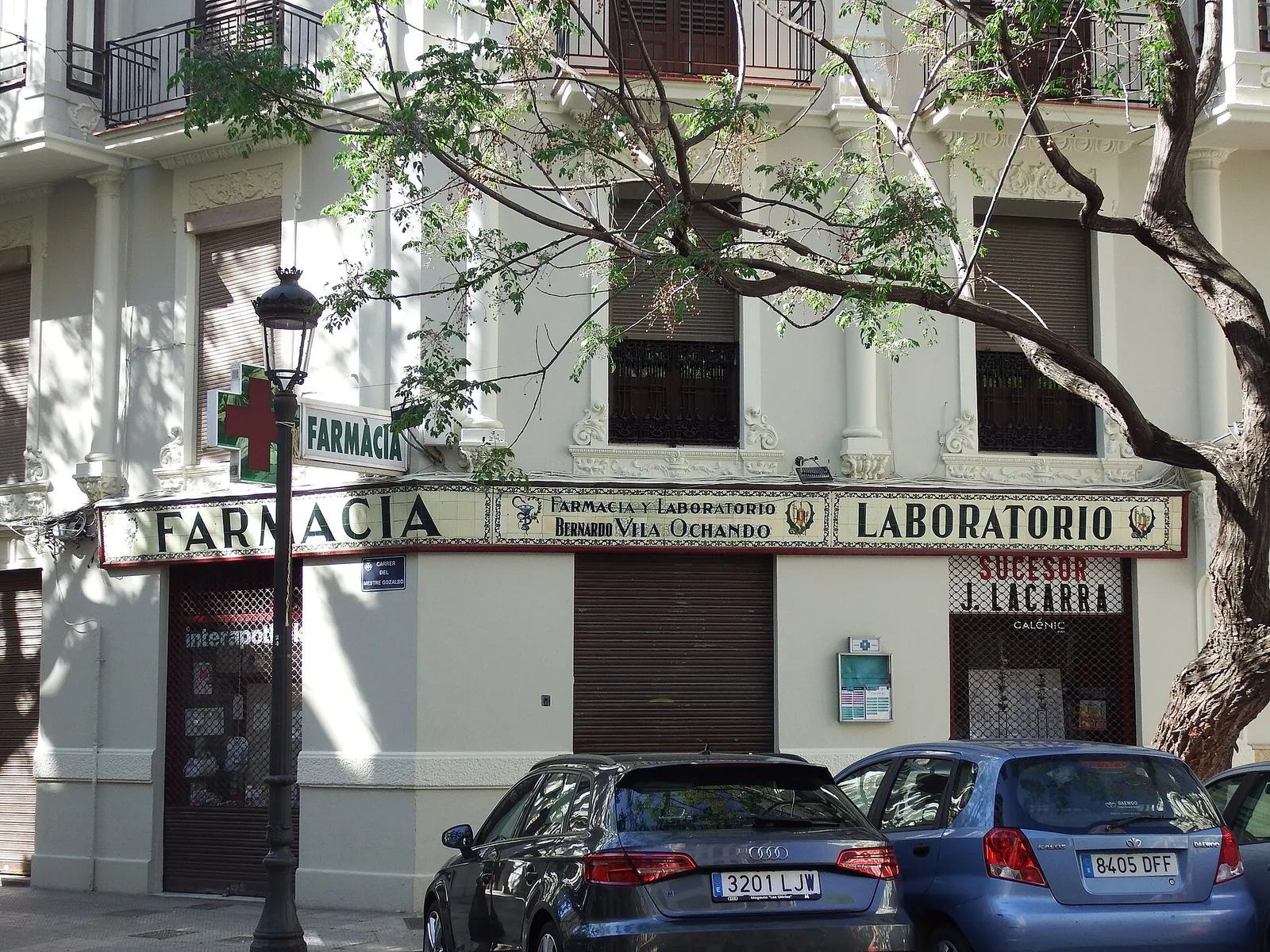 Pharmacy with a green cross on a corner of an old building, cars parked in front