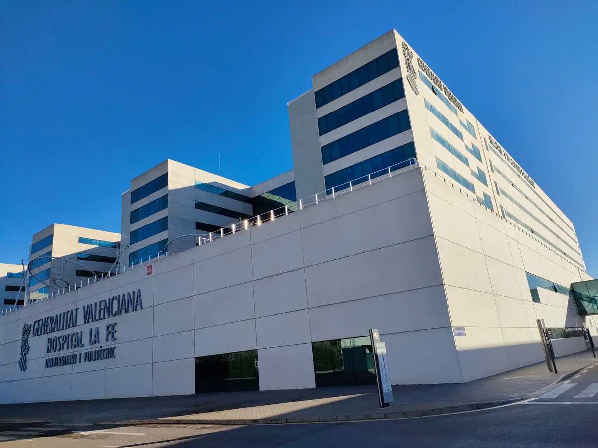 Large white hospital building with rows of blue-green windows under a clear sky