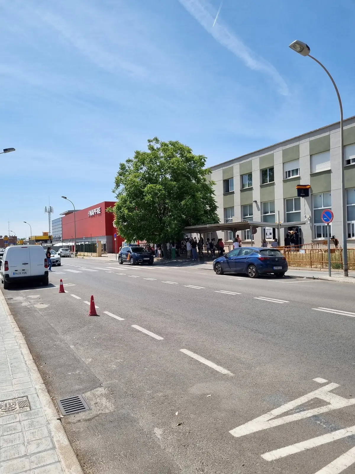 Street in front of the police foreigners office building in Valencia, with a few people waiting near the entrance.