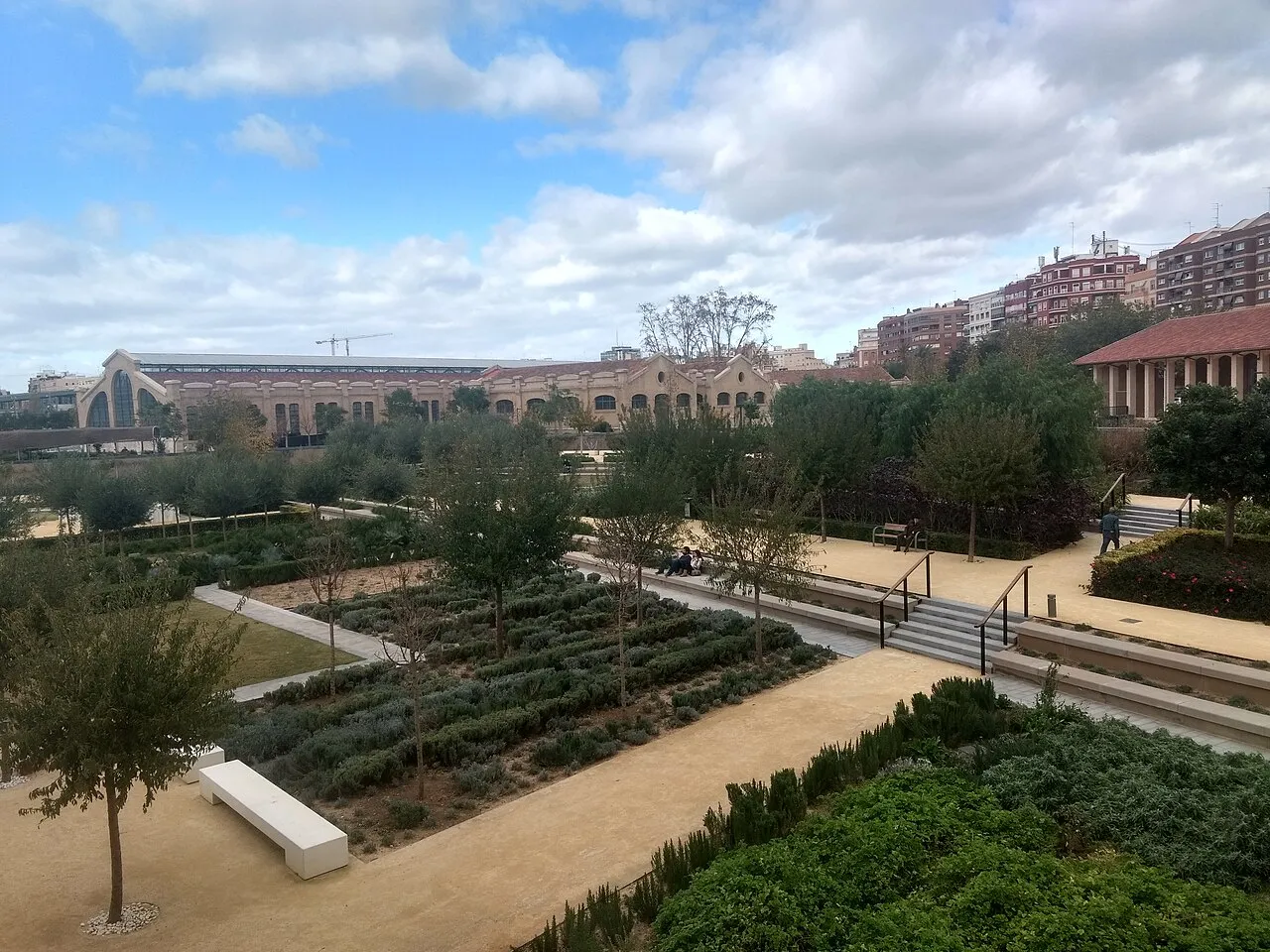 Landscaped paths, hedges and trees in the Parc Central with apartment blocks on the skyline.