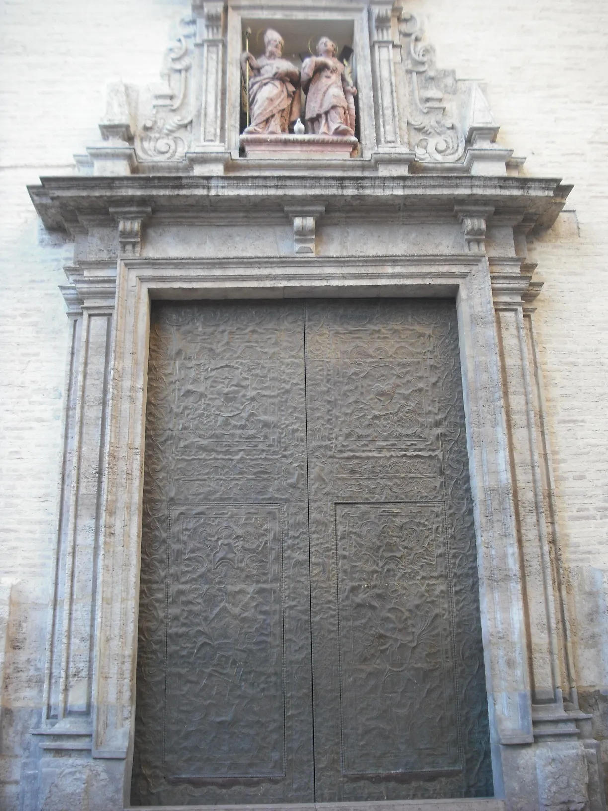 Stone doorway with a carved surround and closed wooden doors on the church of Sant Valero.