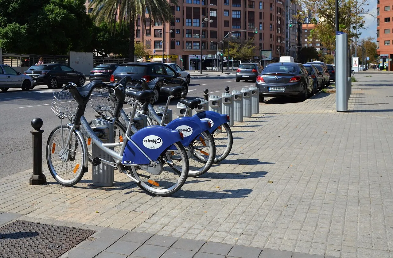 Row of blue Valenbisi bikes docked at a station on a Valencia street