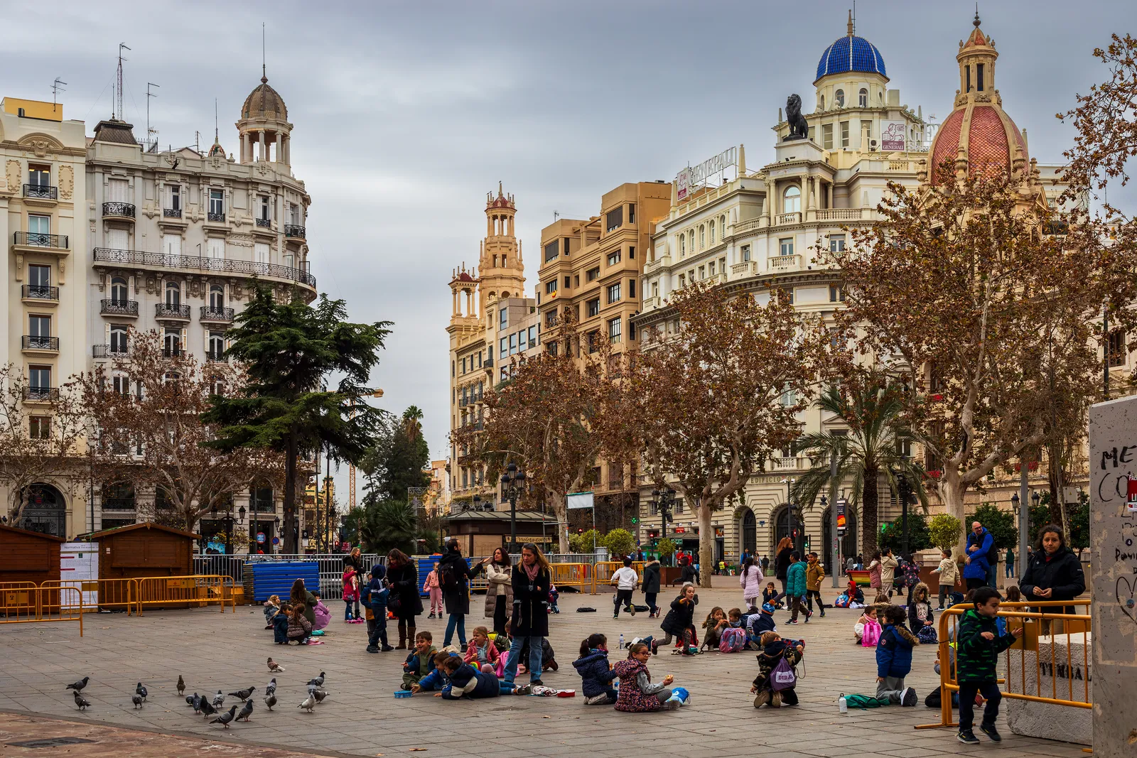 A wide city square in Valencia with a historic building and a fountain